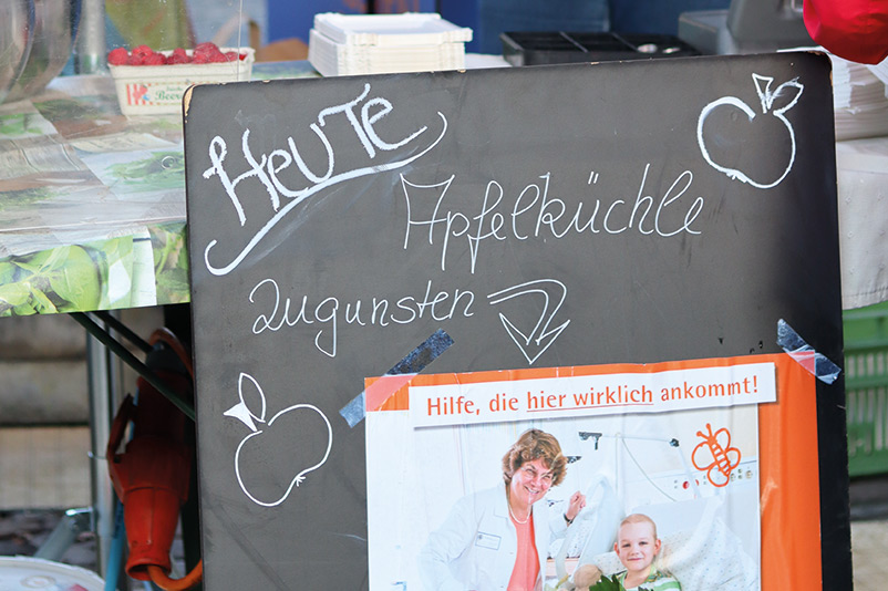 Hinweisschild zur Aktion - Apfelküchle-Verteilaktion von Conny und Walter Schwaab auf dem Münstermarkt Freiburg