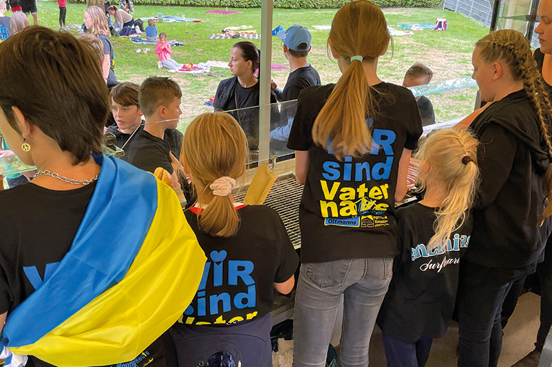 Kinder am Wurstbraten - Ireneus Frost und Daniel Brunner organisieren Sommerfest für ukrainische Waisenkinder.